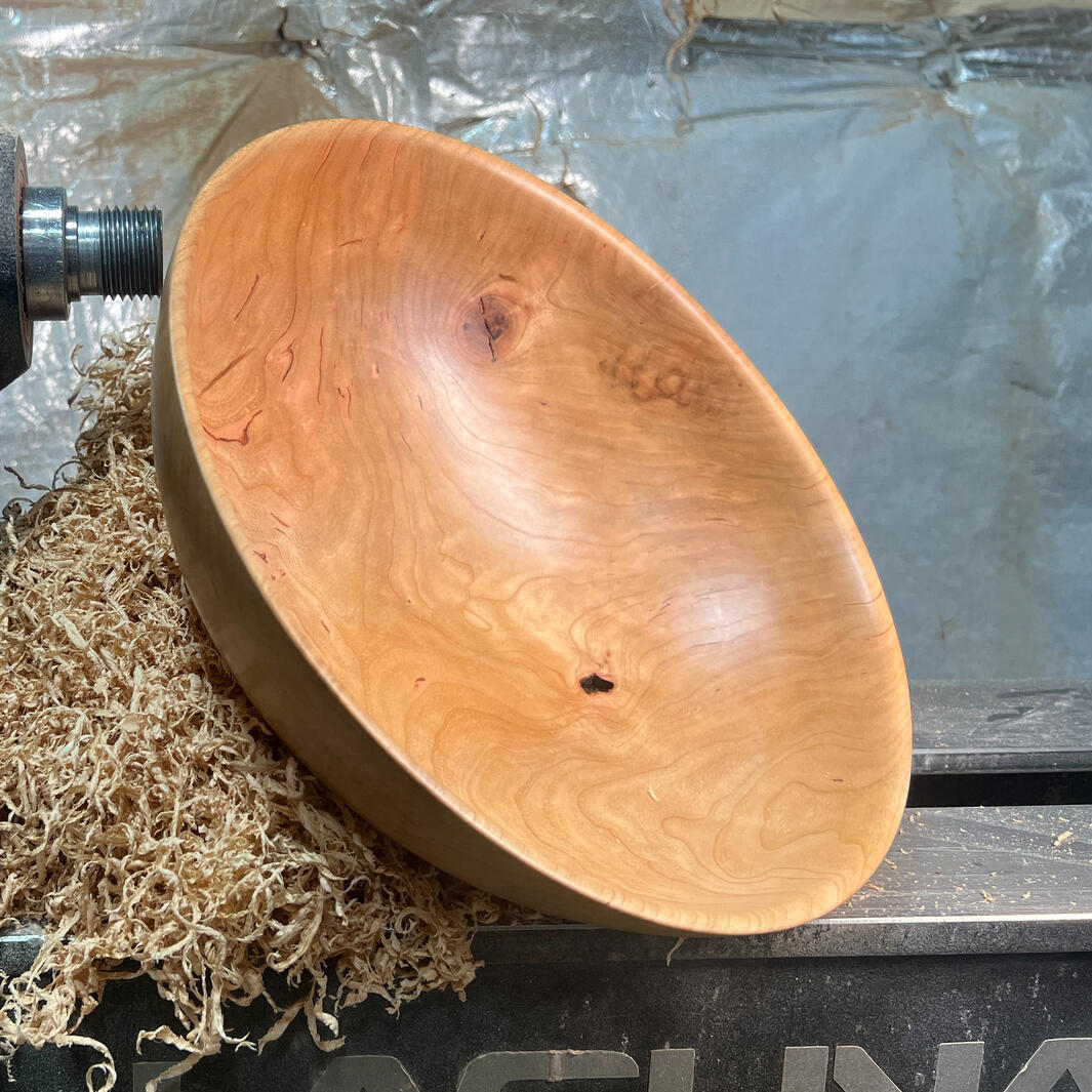 Cherry wooden bowl sitting on a lathe