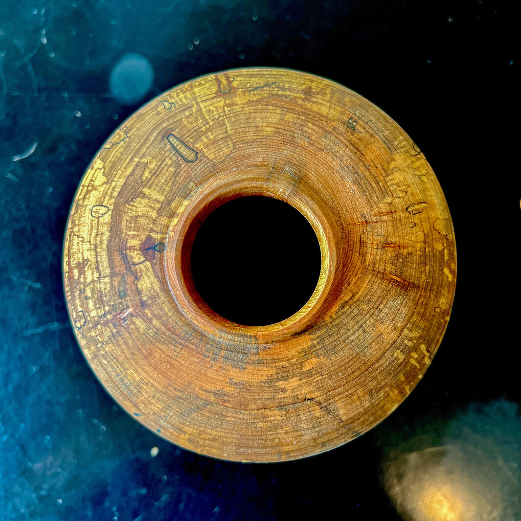 Looking down on a spalted dry vase on a black table