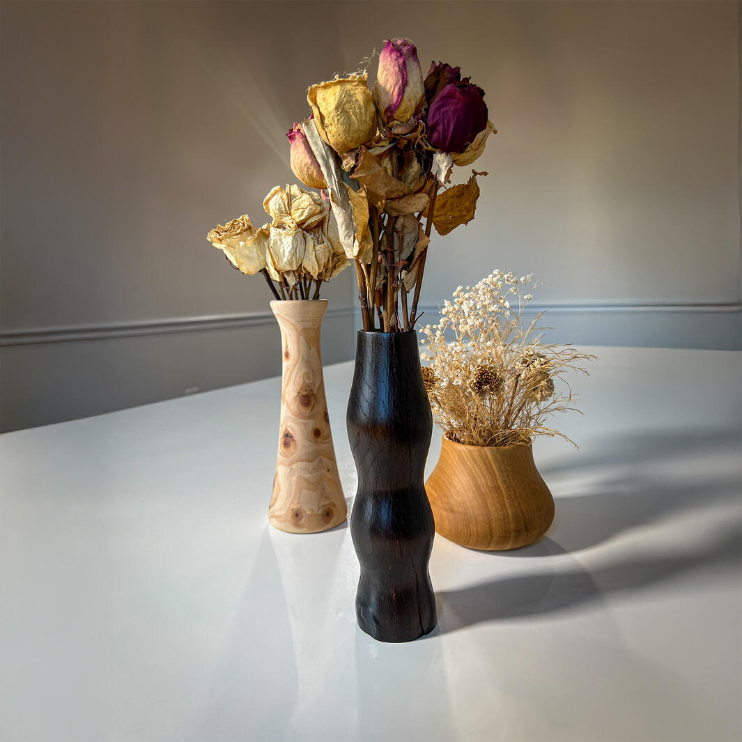 three wooden vases of different shapes with dried flowers in them